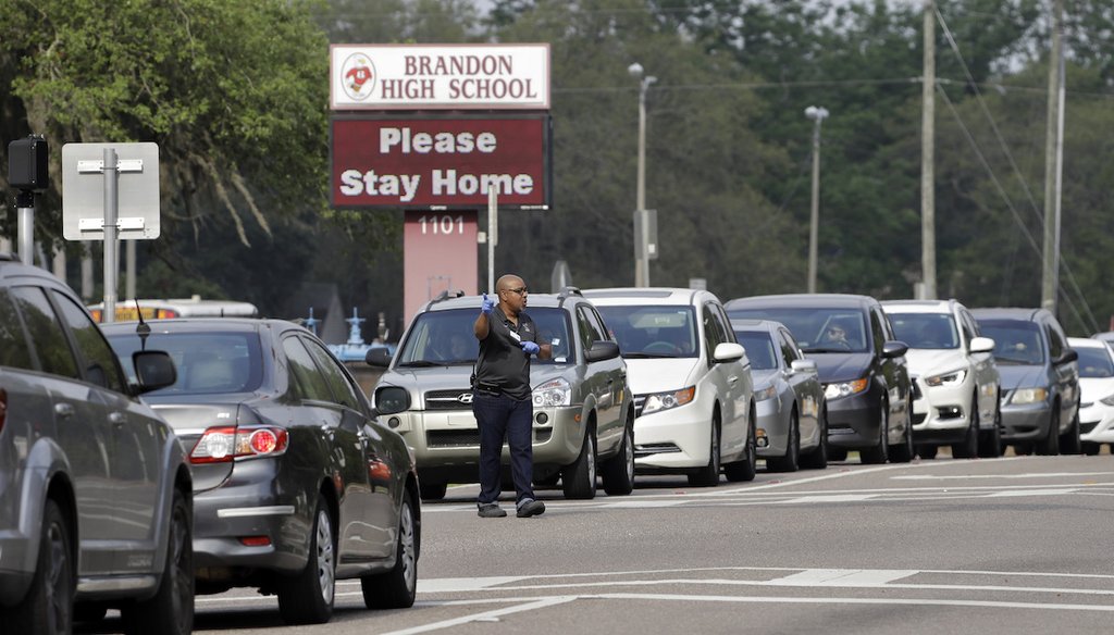 A Brandon High School faculty member directs traffic for parents that are waiting in line to pick up school breakfast and lunches on April 15, 2020, in Brandon, Fla. (AP)